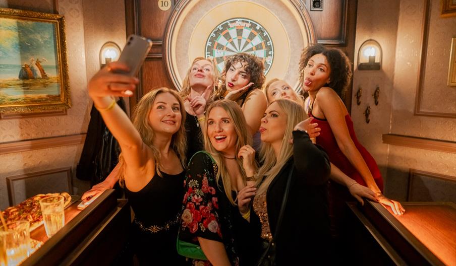 Women posing with dart board