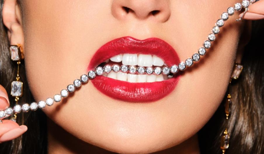 Woman wearing lipstick with jewellery in her mouth