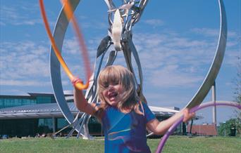 girl with hoola hoop in front of sculpuire