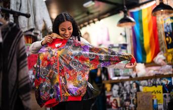 Woman holding up a brightly coloured jacket to herself