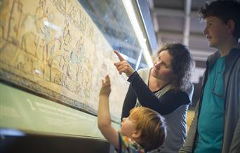 A family looking at the Bayeux Tapestry.