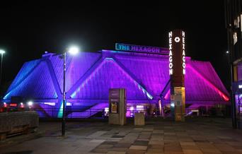 Night time outside the Hexagon with purple lights