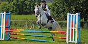 Woman riding a horse over a multicoloured hurdle