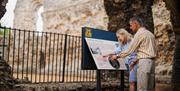 Couple looking at information board at Reading Abbey Ruins