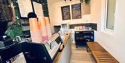 Interior with a bench, blackboard menus and stacked orange disposable cups