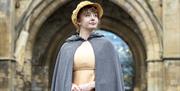 'Jane Austen' in period dress in front of Reading Abbey Gateway