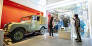 Visitors looking at a display that includes a pair of wellies used on Worthy Farm and a Land Rover.