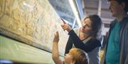 A family looking at the Bayeux Tapestry.