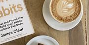 handmade gluten free millionaire's shortbread cake with a latte with latte art. relaxing morning or afternoon treat along with a book