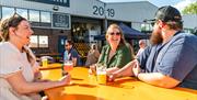 Three friends having beer outside at a yellow table