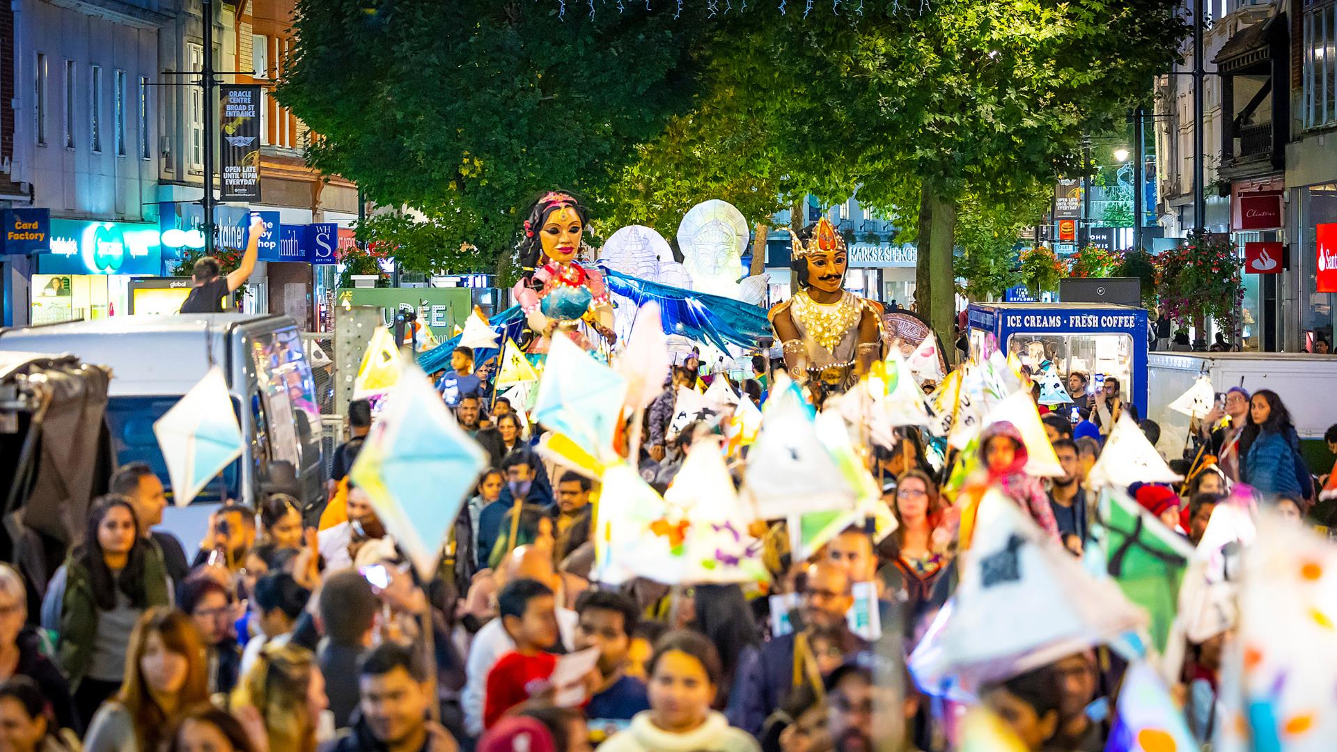 Crowd celebrating Diwali carrying lanterns through Reading's Broad Street