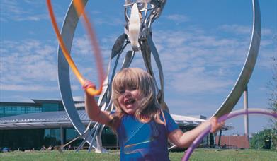 girl with hoola hoop in front of sculpuire