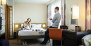 A couple talking in a hotel bedroom.