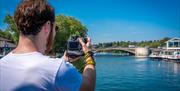 Man taking a photo onboard of the river and Caversham Bridge