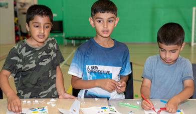 3 young children working on arts and crafts.