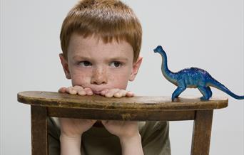 A child with a dinosaur toy.
