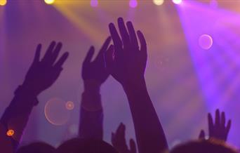 People at a concert with arms in the air