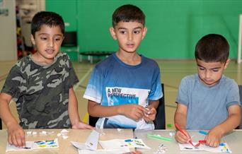 3 young children working on arts and crafts.