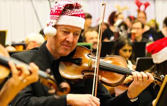 An orchestra wearing Santa hats.