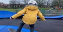 Boy riding a skateboard on a pump track at Hopwood Park.