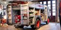 A vintage fire engine with equipment compartments open for display.