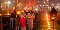 Family walking along footpath lit with flaming torches.