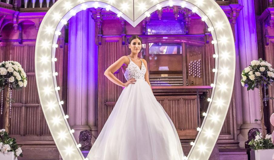 A bride posing in a giant illuminated heart.