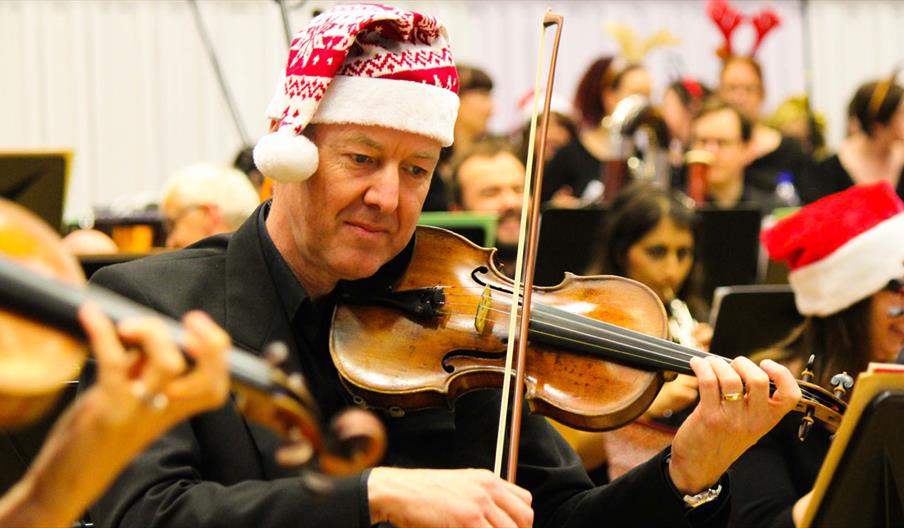 An orchestra wearing Santa hats.
