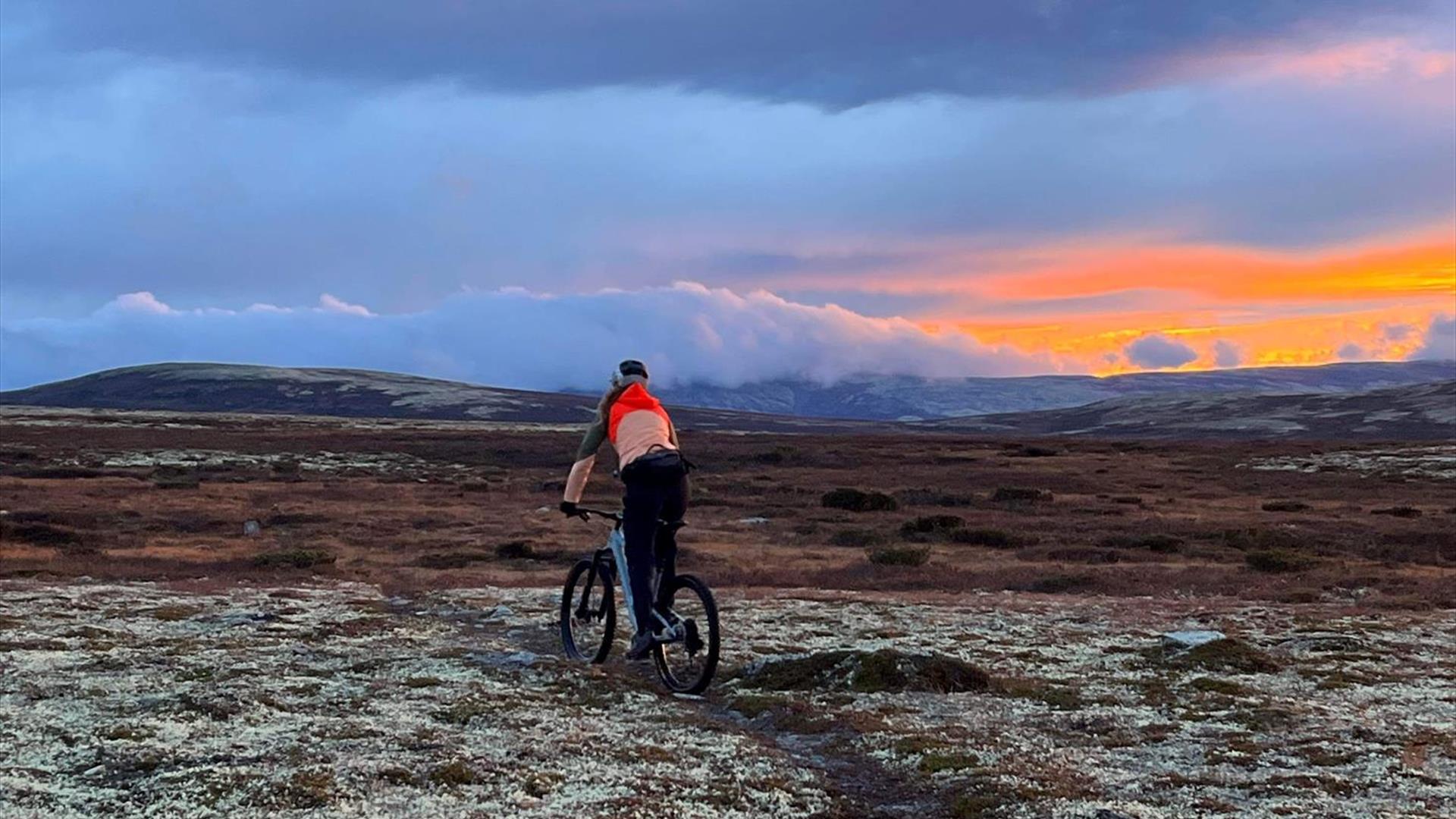 Stisykling på fjellet med blå himmel og orange solnedgang.