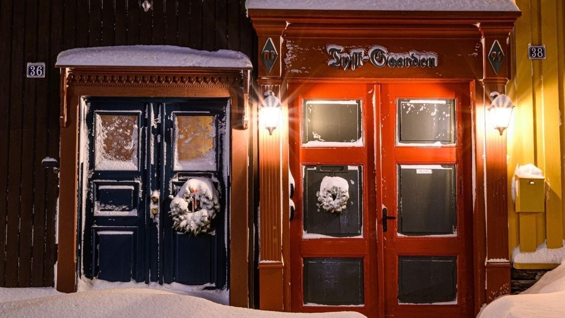 Julestemning på Røros med snø på gamle husvegger og julekranser på dørene