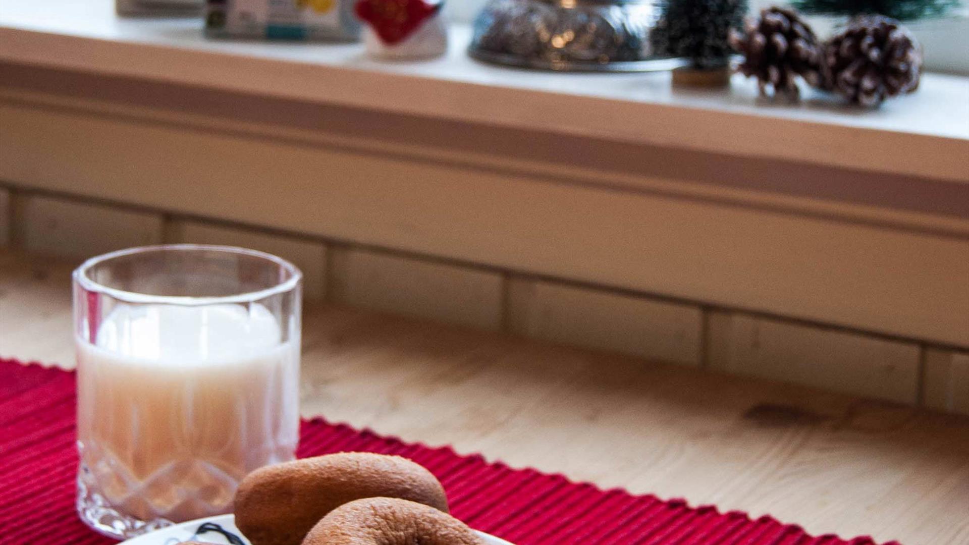 Smultringer og et glass melk på en rød juleløper. Laget av Rørosmeieriet.