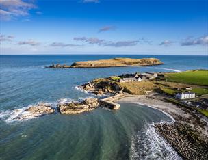 An aerial view of Port Muck showing the sea crashing into the headland.