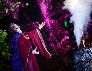 A woman in Halloween costume singing with smoke & lights in background