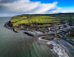 Glenarm harbour from an aerial view showing boats in the harbour and the hills and coast road behind