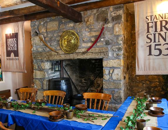 Room set up for Dobbins dining experiece as part of Dobbins Dander and Dine with seats and long tables in front of a large fireplace.