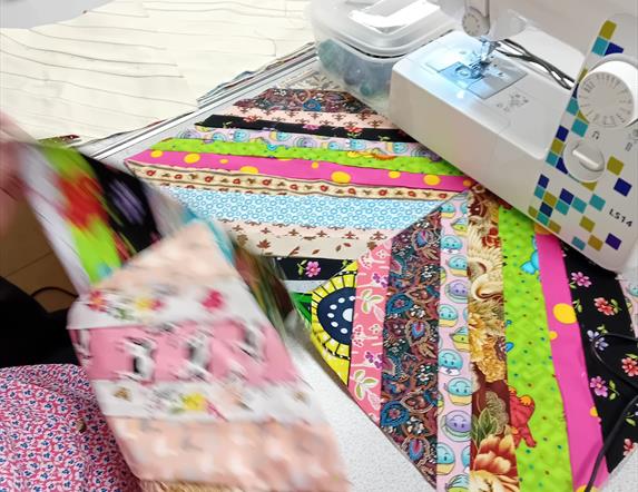 Sewing machine and patchwork quilt in progress at Midtown Makers workshop