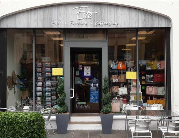 Grey exterior building of ETC Carrickfergus with entrance door and full windows plus outside seating area showing silver tables and chairs plus fake h