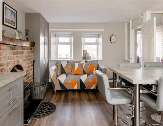 Open plan sitting area with kitchen table front door and a fireplace.