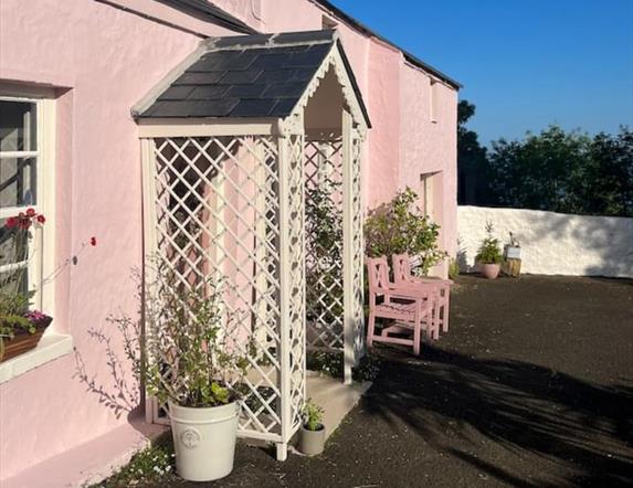 Outside view of the pink cottage with trellis porch