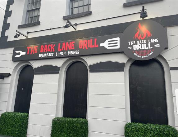 Exterior sign for The Back Lane Grill in red and white writing on black background