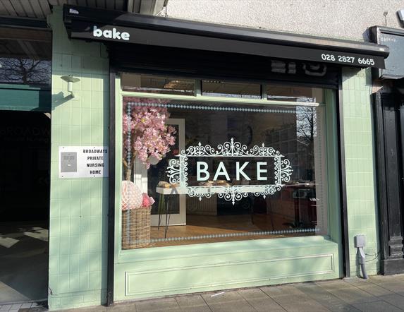 Exterior of Bake bakery in Larne painted light green with black canopy and word BAKE in large window