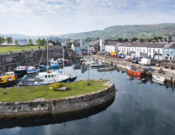 Aerial view of Carnlough Harbour with shops and homes in the background and boats in the harbour