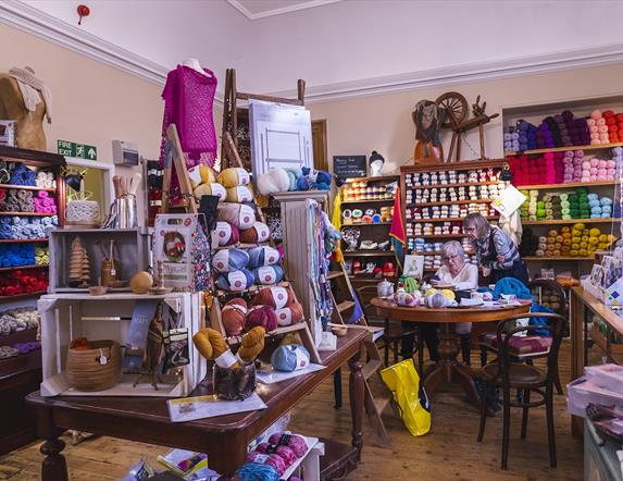 Interior of Lighthouse Yarns with lots of wool displays and people at the crafting table