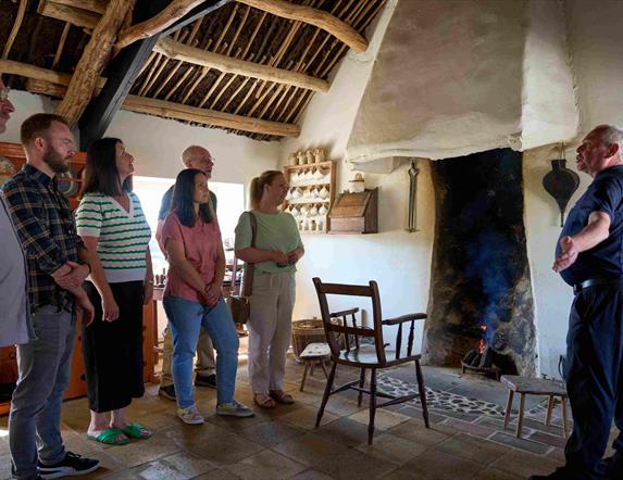 A group of visitors listening to the tour guide inside Andrew Jackson Cottage standing by the fire.