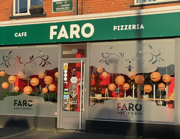 Large windows with FARO branding and green signage - Exterior shop frontage of Faro Cafe & Pizzeria at Halloween