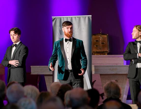 3 individuals in suits performing opera in a church venue