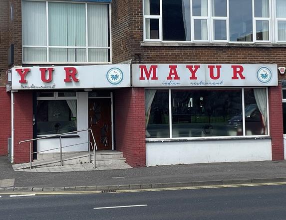 Exterior of Mayur Indian restaurant with sign in red and white, plus whote and red walls