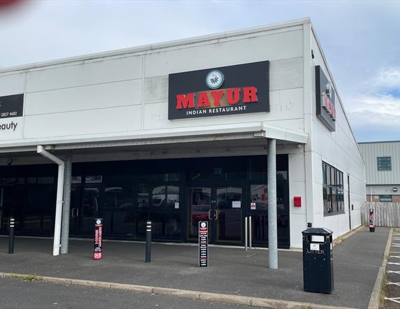 Exterior of Mayur Indian Restaurant in Larne with grey bulding and black windows / door