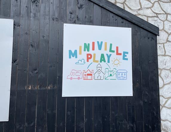 Miniville Play Sign featuring the words plus llustrated images of ice cream van, shop, church, house and castle.