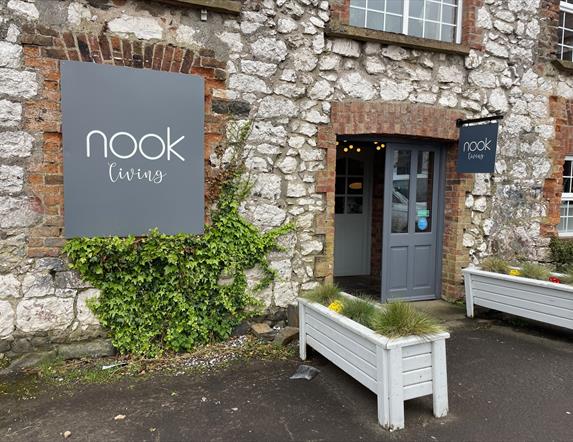 Brick exterior of Nook Living with grey signage and white planter